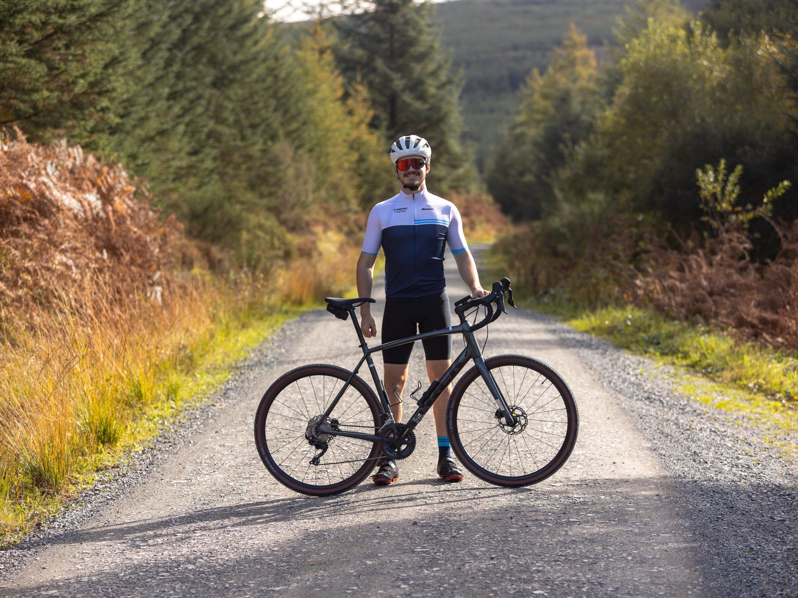 A cyclist standing on a gravel road with their bike