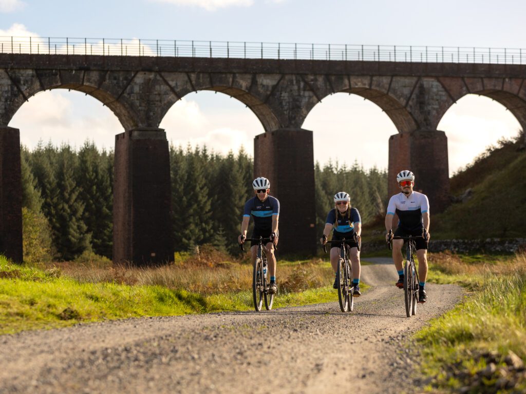 Cyclists riding through Big Water of Fleet Viaduct with 70 foot high granite arches