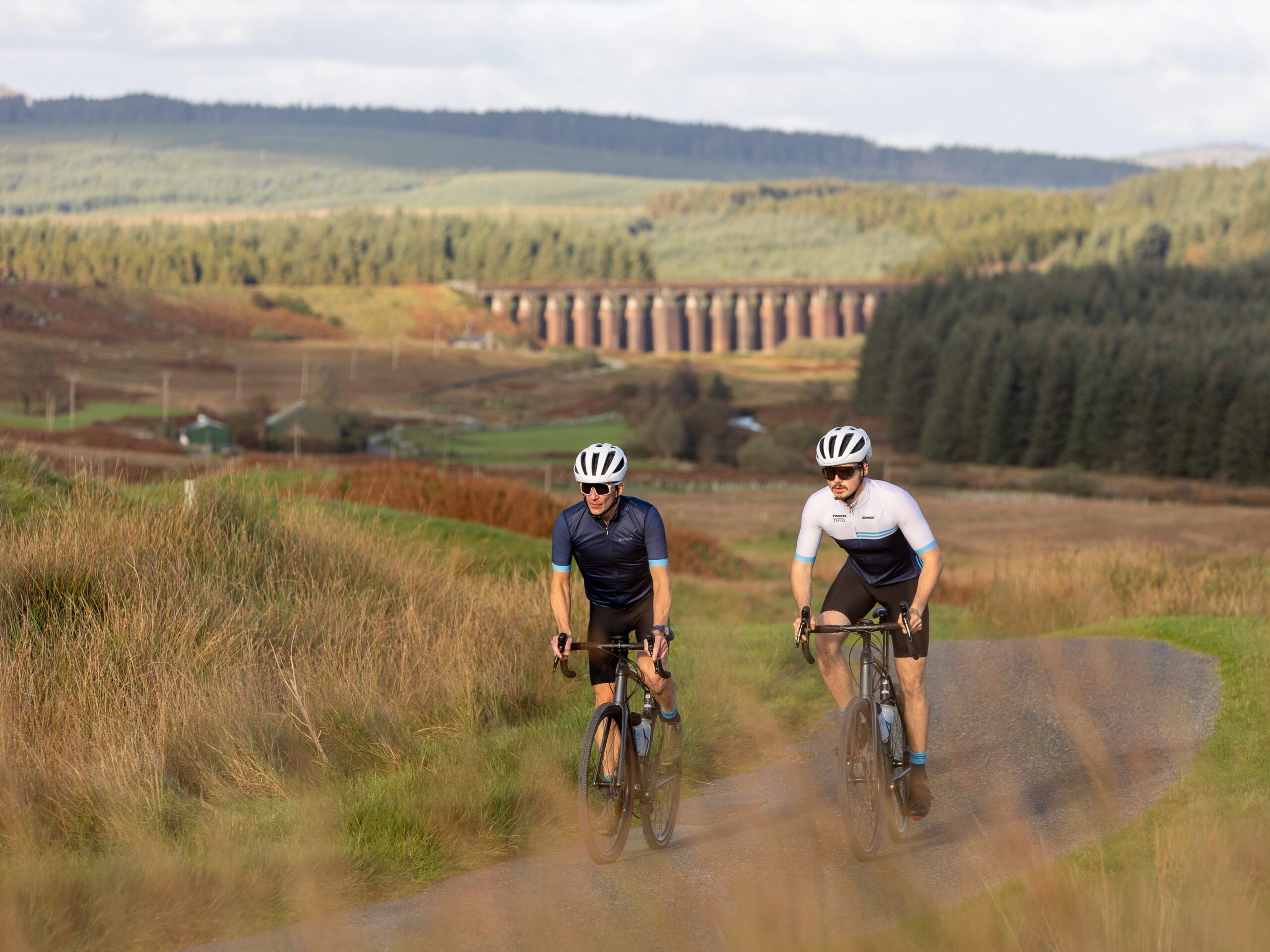 cyclists on path with viaduct in background