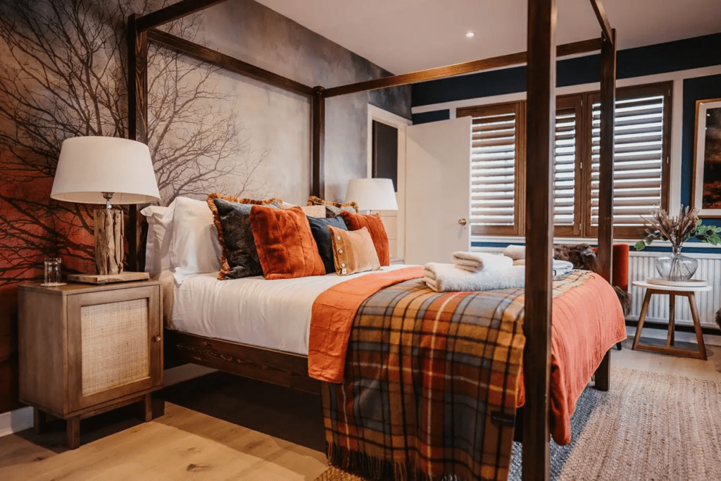 Four-poster double bedroom with pillows and tartan cover