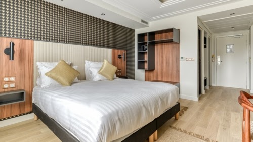 Double bedroom with patterned wallpaper and wood floors at Zenitude Relais & Spa