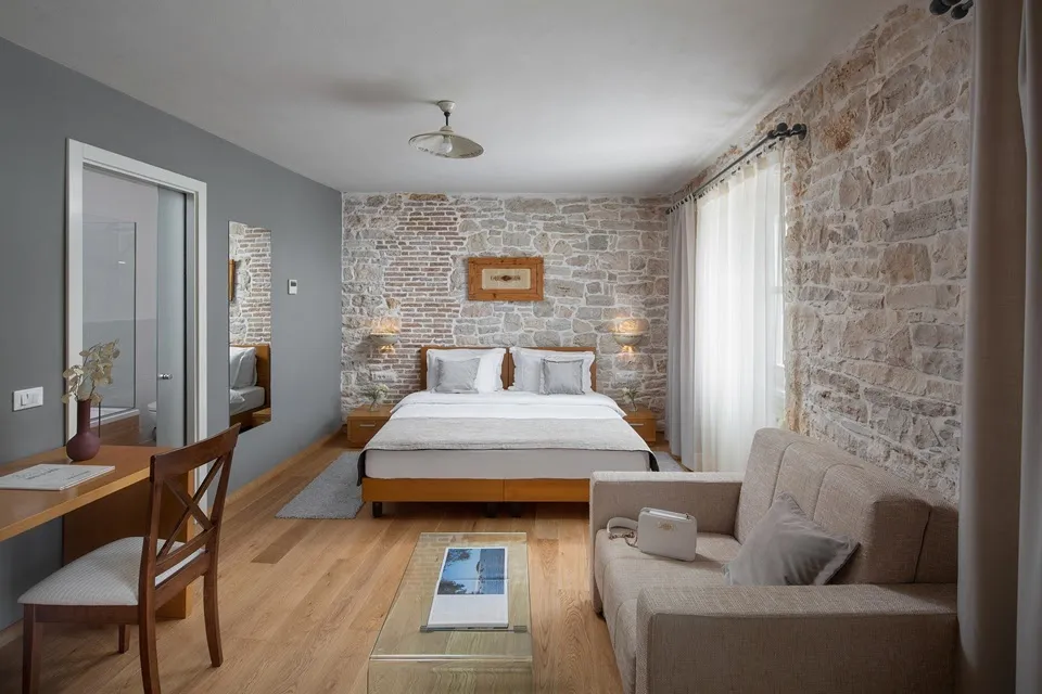 Double bedroom and sofa with exposed brick walls at Hotel La Grisa