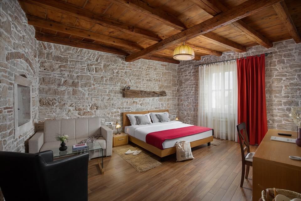 Double bedroom with sofa and stone walls at Hotel La Grisa
