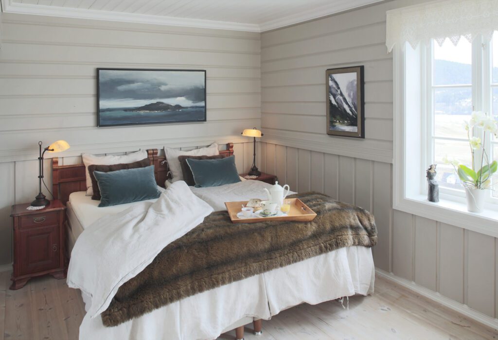 Double hotel bedroom with painted wood panelling and a breakfast tray on the bed
