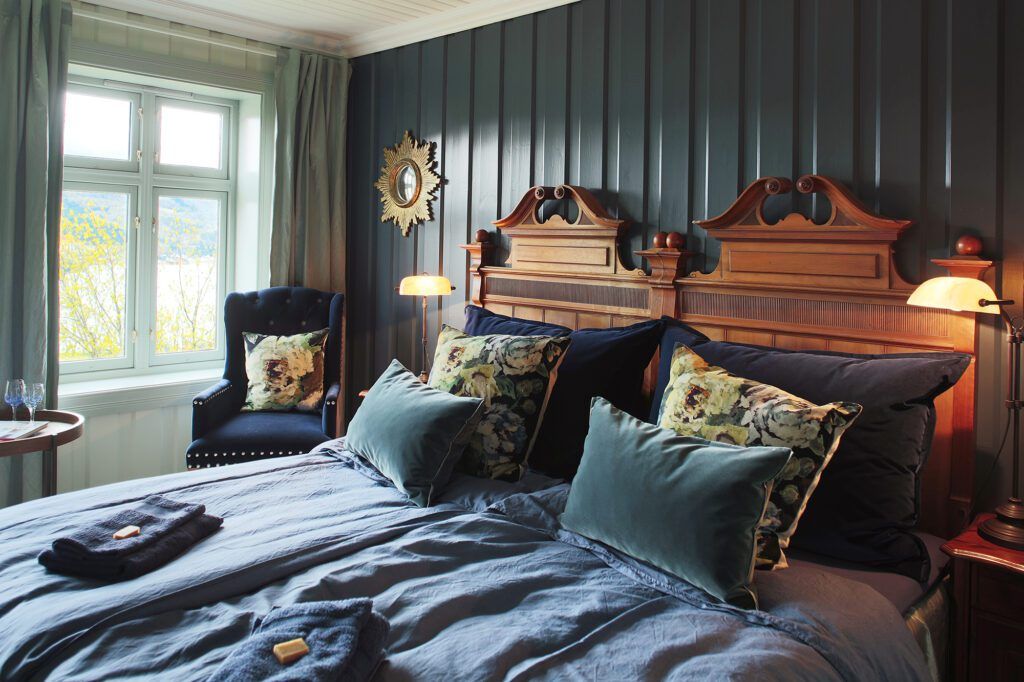 Double hotel bedroom with dark colors, decorative pillows and fancy wood head board