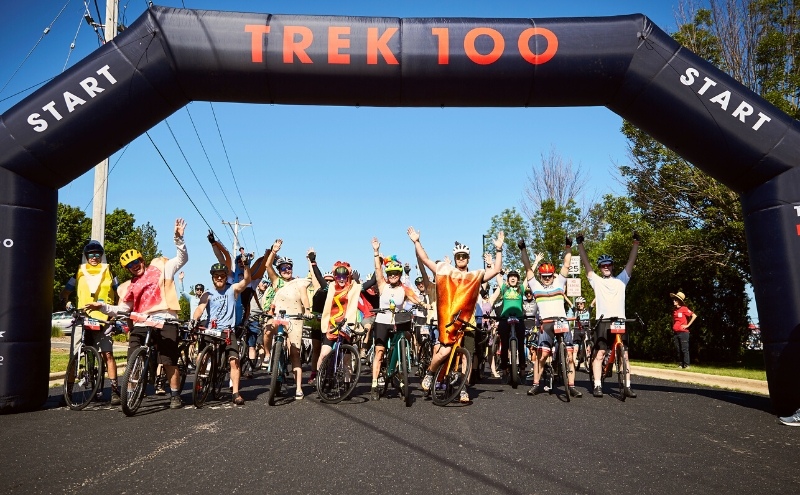 Group of costumed cyclists at the start line of the Trek 100
