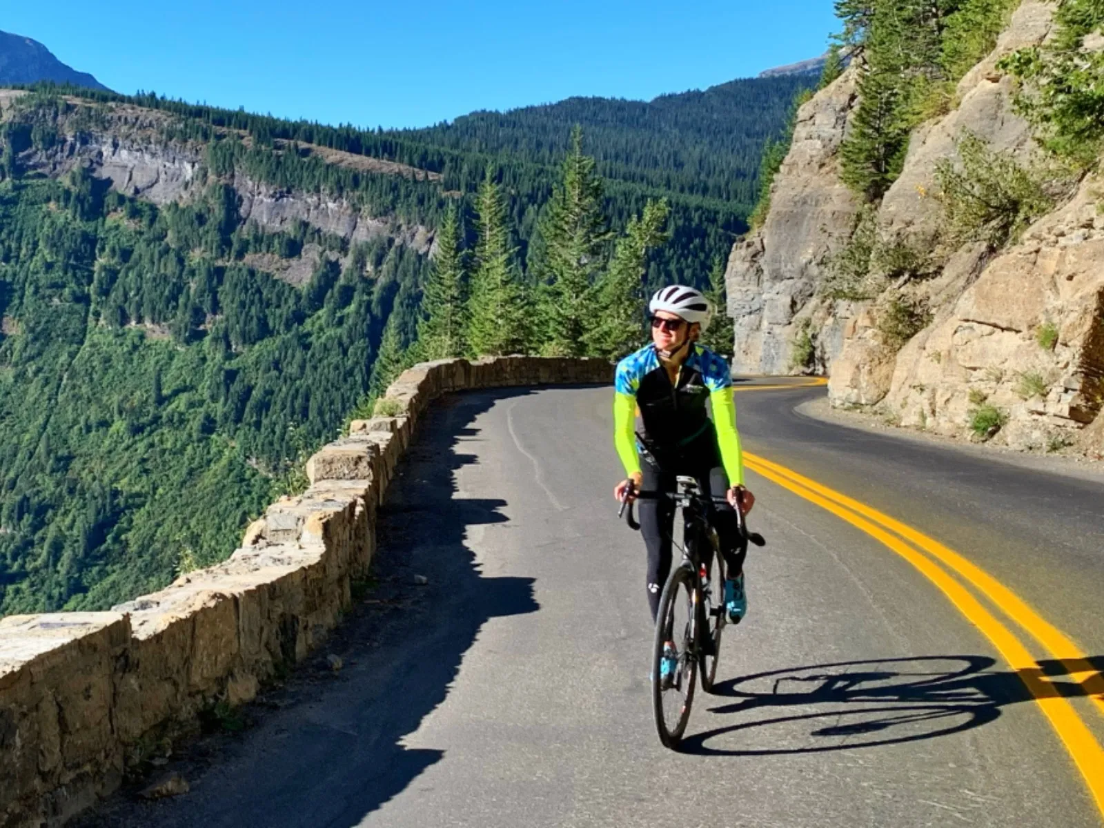 A cyclist rides on a twisty mountain balcony road