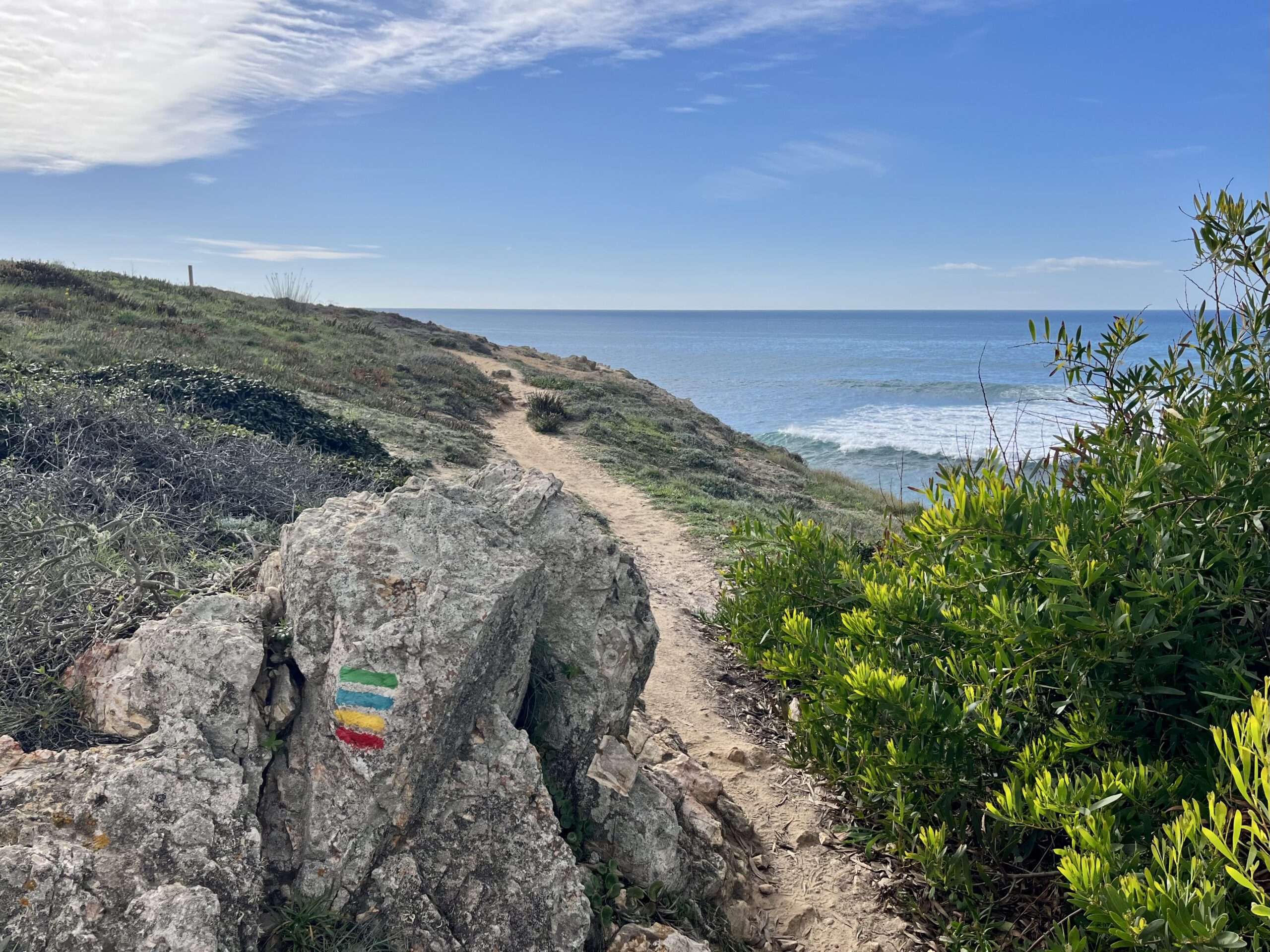 A single track on the coast of Portugal, with a hiking mark on a stone