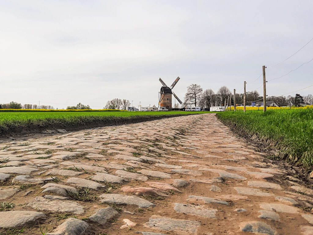 A landscape shot of cobbles in Belgium with a windmill in the background