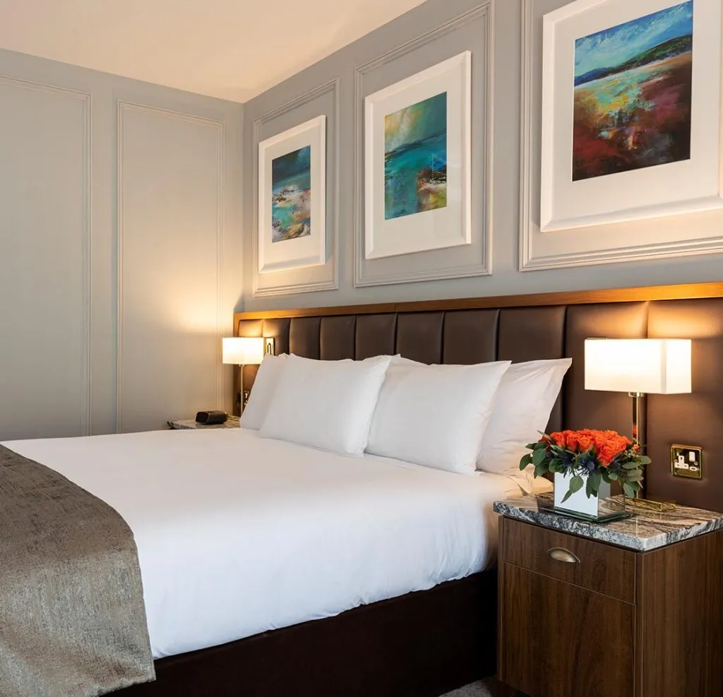 Double bedroom with padded headboard and three framed paintings on the wall