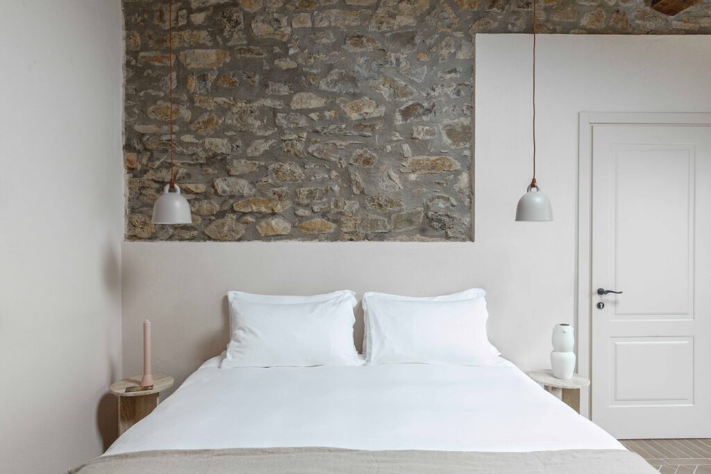 Double bedroom with pendant lamps and stone wall at Pieve Aldina